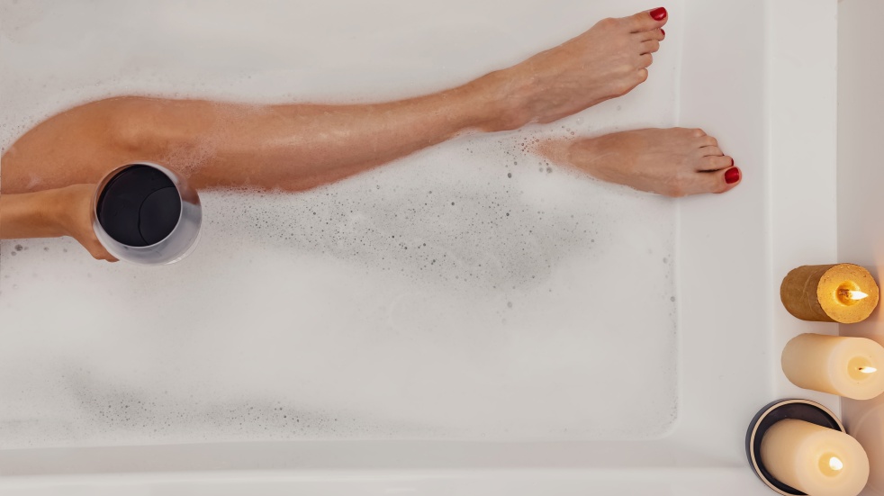 woman lying in bath with wine and candles